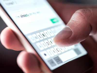 A hand typing a message on a smartphone screen with a keyboard displaying the typed text.