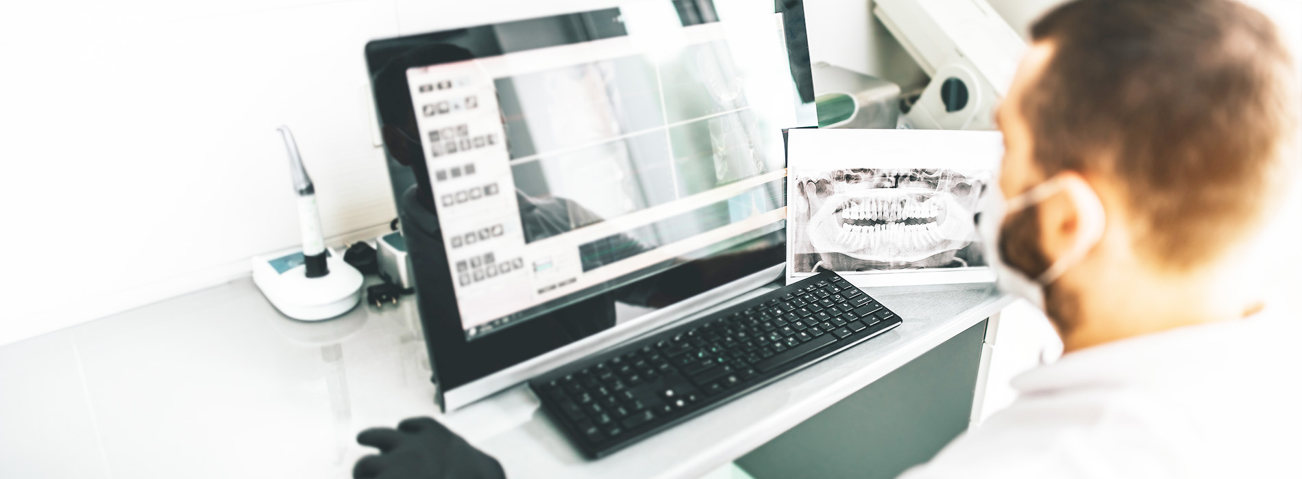 A person seated at a desk with a laptop, monitor, and keyboard in front of them.