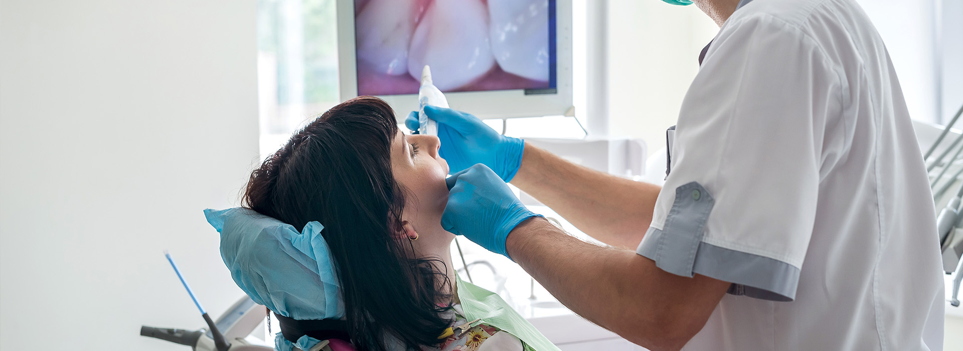 A dental hygienist is performing a cleaning procedure on a patient s teeth in an office setting.