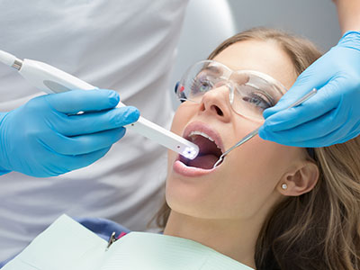 A dental professional using a device to clean a patient s teeth during a dental procedure.